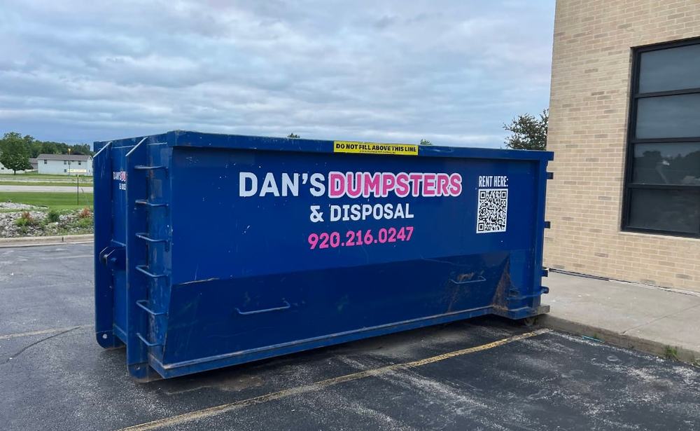 Dan's Dumpsters truck setting a branded dumpster in a driveway in the Fox Valley, Wisconsin