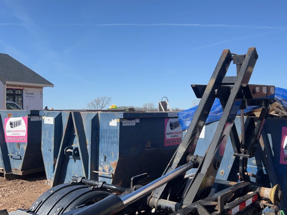 A roll-off dumpster and hooklift set up at a job site, ready for contractor debris